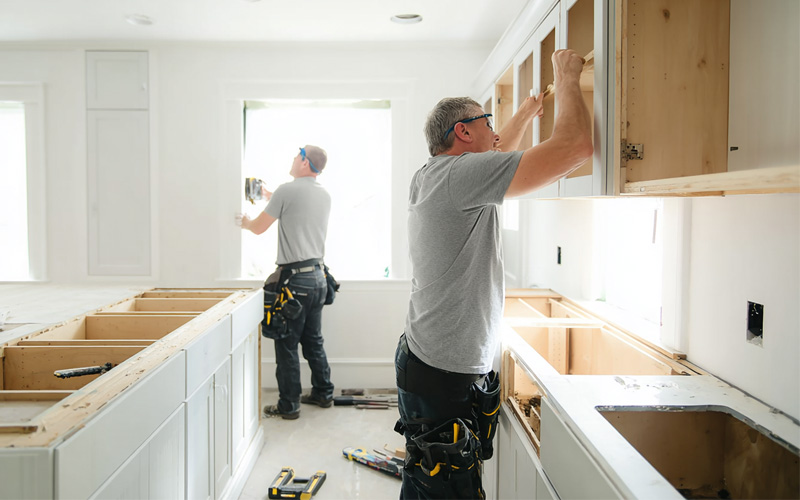 services_0003_Layer 5 Two carpenters installing timber kitchen cabinets in a white kitchen