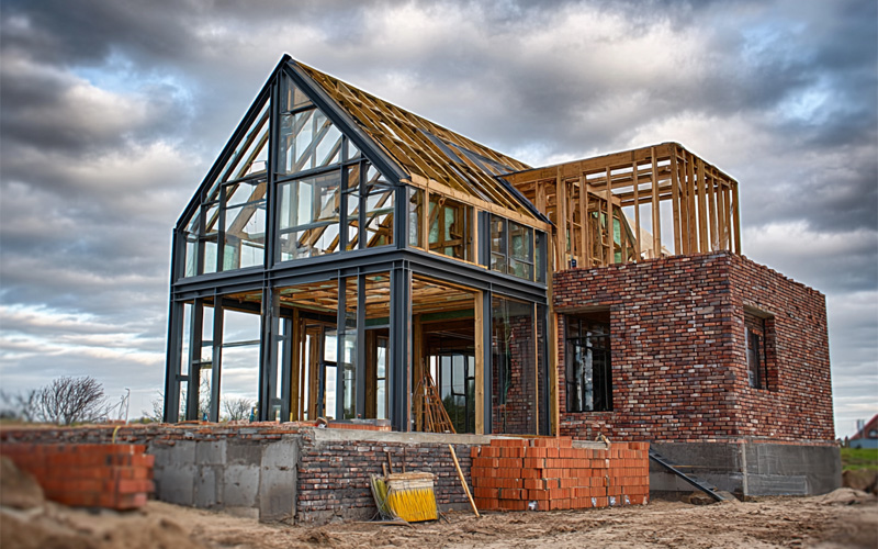 services_0007_Layer 1 New house under construction with a steel and glass gable, timber framing and brick walls